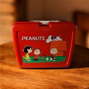 Vintage red plastic Peanuts lunch box featuring the gang around a campfire